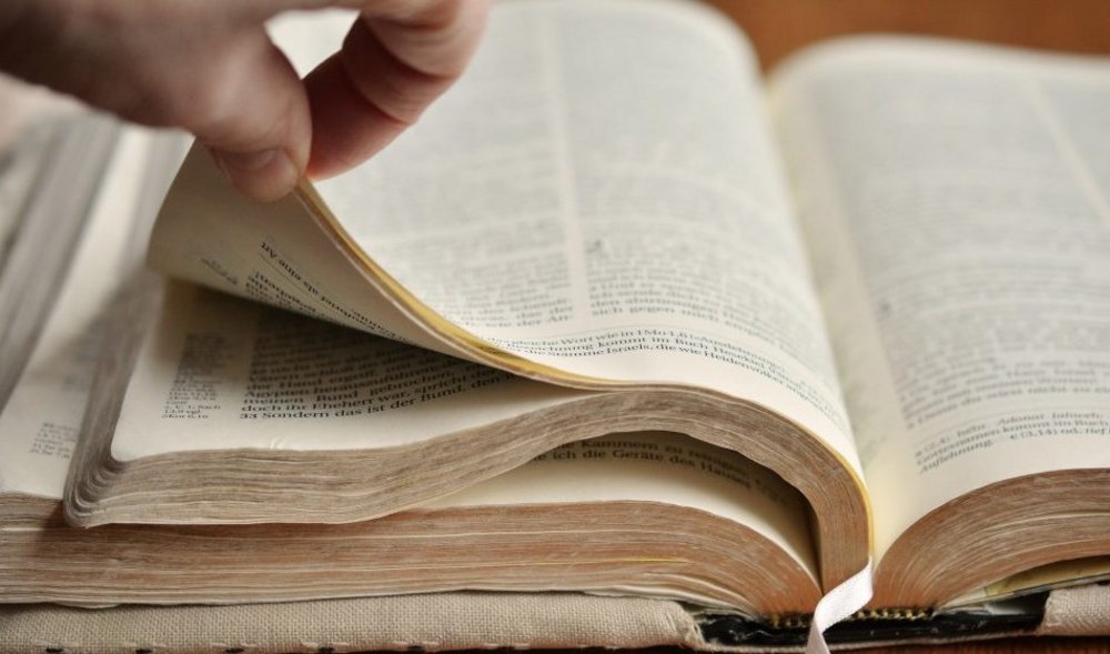 Eine Hand, die in einer aufgeschlagenen Bibel blättert