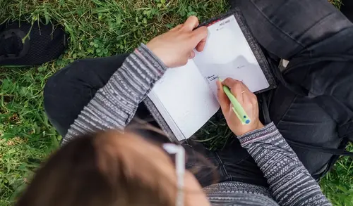Eine Studentin auf einer Wiese auf dem Campus der Universität Erfurt