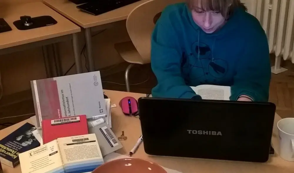 Eine Studentin sitzt während des 24-Stunden-Hausarbeitenmarathon der Lernwerkstatt vor ihrem Laptop, neben ihr liegen Bücher und sie schreibt an ihrer Hausarbeit