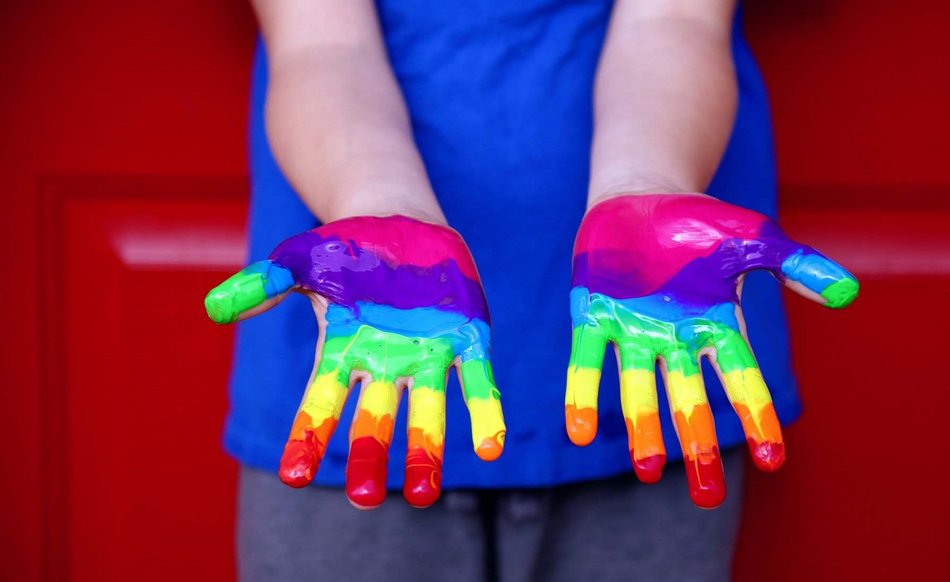 Hände, die in Regenbogenfarben bemalt sind