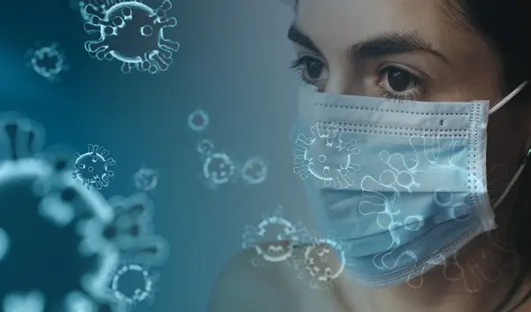 Eine Frau trägt eine Maske, vor ihr Viren in der Luft