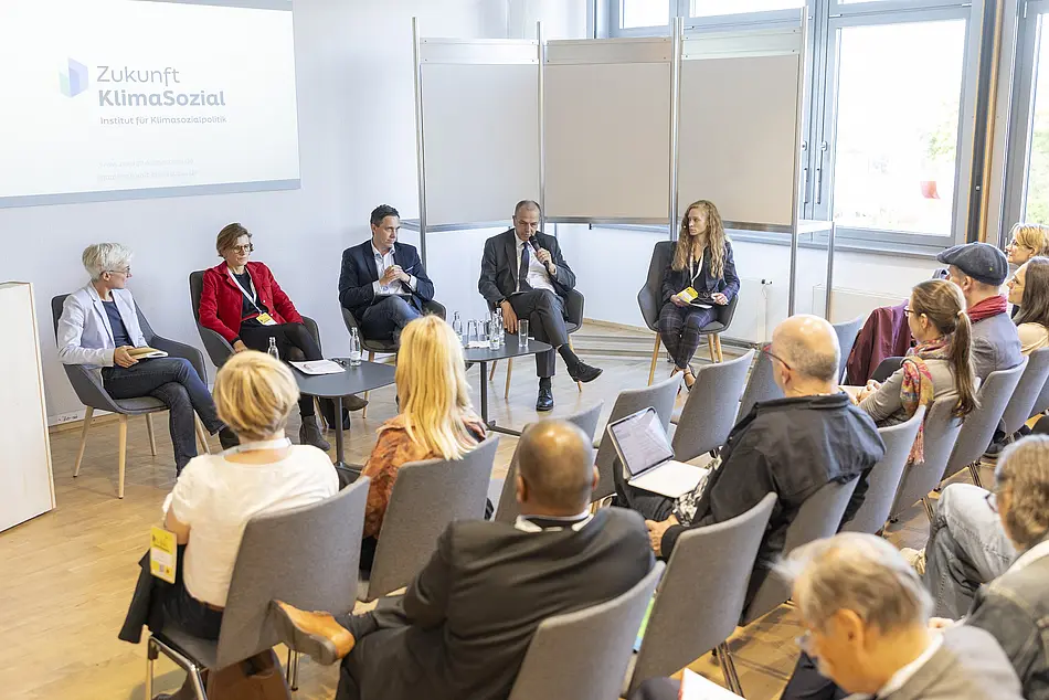 Menschen sitzen auf einem Panel, davor Publikum