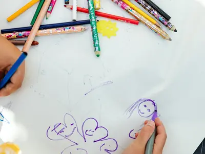 Kleines Kind im Anschnitt zu sehen malt mit Buntstiften