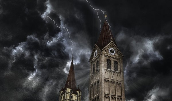 Kirchturm vor dem Hintergrund dunkler Wolken, der vom Blitz getroffen wird