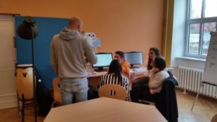Studierende sitzen vor Computern der Lernwerkstatt und diskutieren mit Marcus Berger