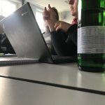 Blick auf ein Laptop und eine Flasche Wasser, im Hintergrund Teilnehmer:innen der 11. internationalen Lernwerkstättentagung in Erfurt