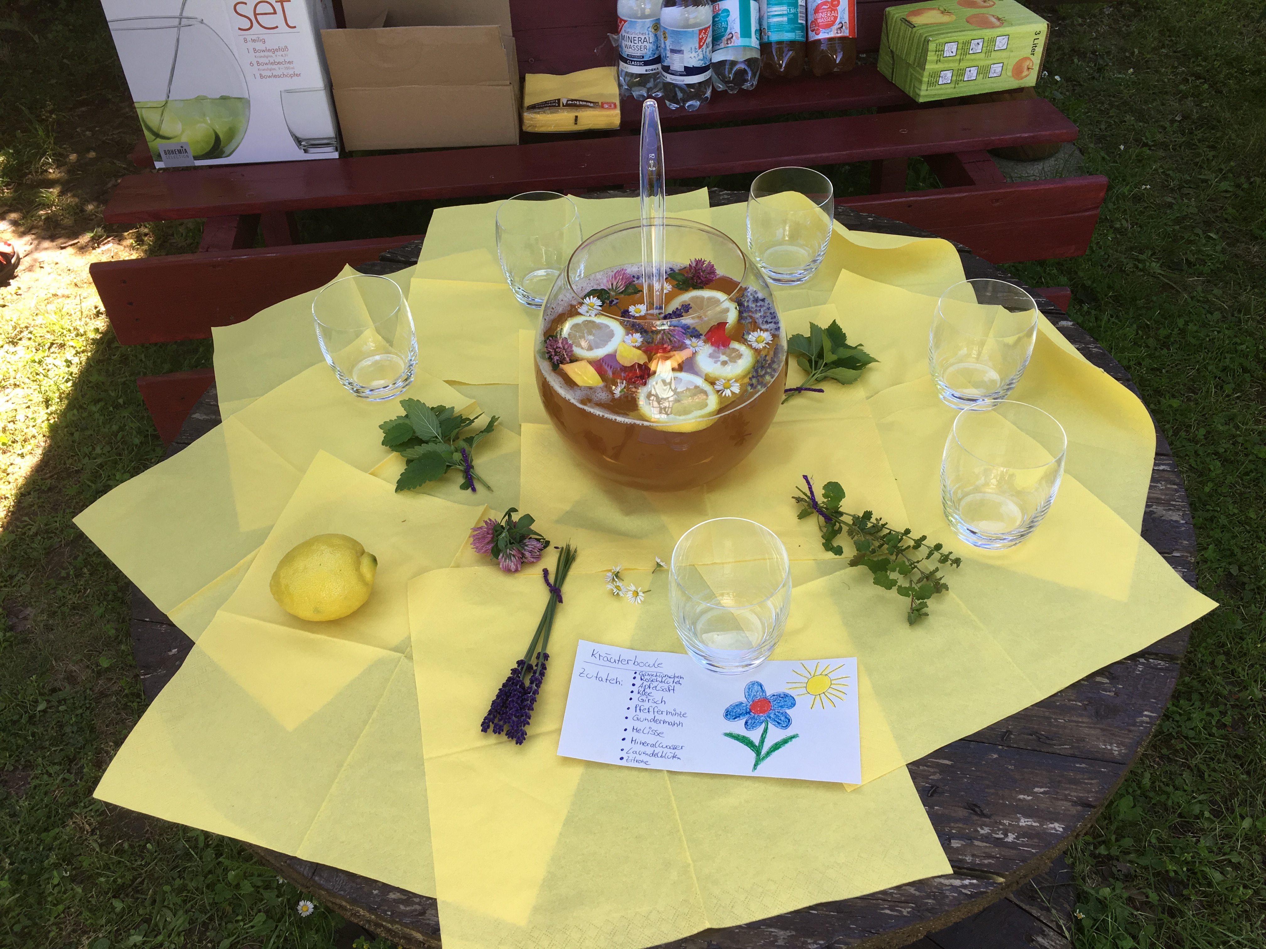 Tisch mit Servietten, Gläsern, Dekoration und in der Mitte eine Kräuterbowle im Rahmen der Ernteverwertung des Campus-Schulgartenfests